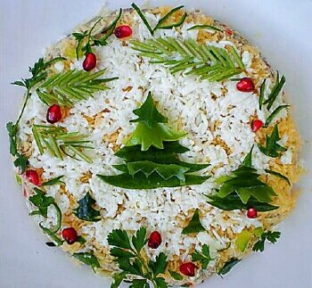 Сверху украшаем новогодний салат оставшимся белком, веточками петрушки